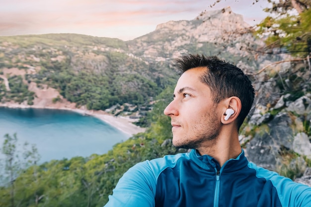 l'uomo cammina lungo un sentiero panoramico immerso nella bellezza della natura mentre ascolta la sua musica preferita attraverso gli auricolari