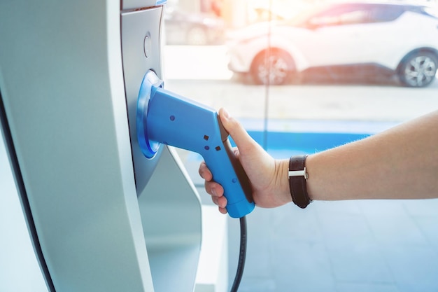 L'uomo carica la sua auto elettrica alla stazione di ricarica della città