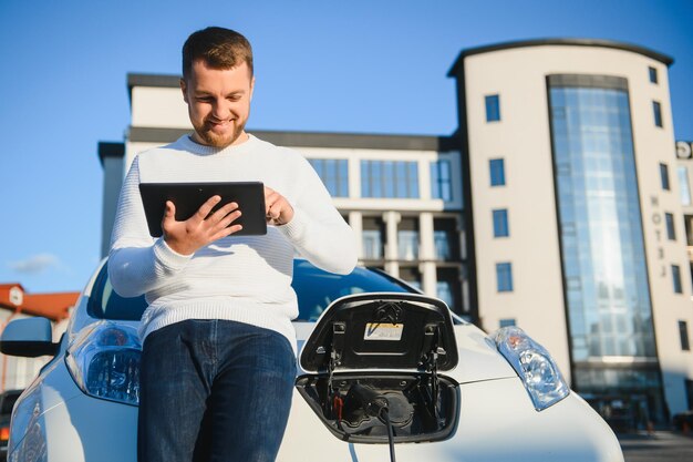 L'uomo carica un'auto elettrica alla stazione di ricarica