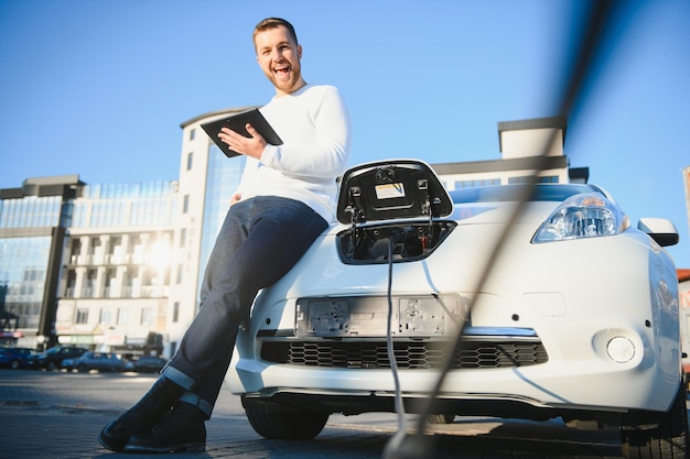 L'uomo carica un'auto elettrica alla stazione di ricarica