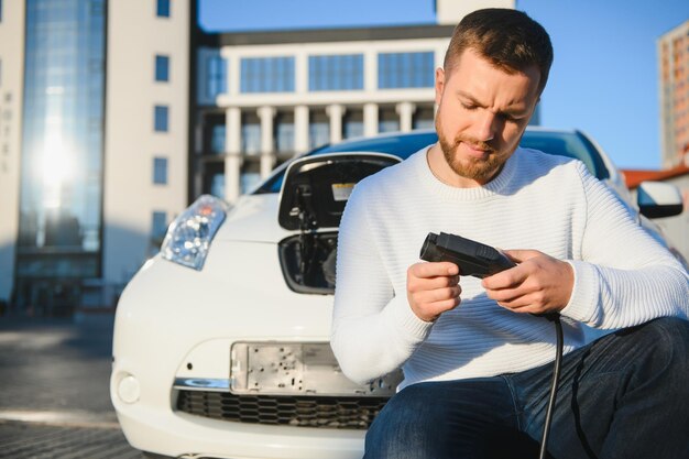 L'uomo carica un'auto elettrica alla stazione di ricarica