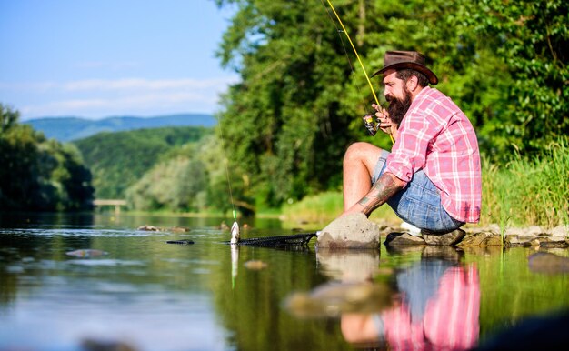 L'uomo cattura il pesce L'uomo sulla riva del fiume gode di un paesaggio idilliaco tranquillo mentre pesca Guy pesca con la mosca Pesca con la mosca di successo Hobby per l'anima Uniti con la natura Tecnica di pesca del pescatore usa la canna