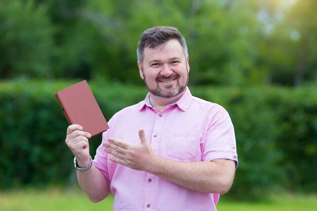 L'uomo caucasico di mezza età felice in camicia rossa con piacere mostra un nuovo libro