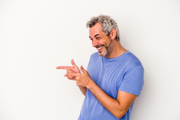 L'uomo caucasico di mezza età isolato su sfondo bianco punta con il dito pollice lontano, ridendo e spensierato.