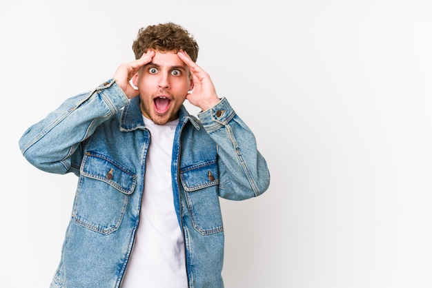 L'uomo caucasico giovane dei capelli ricci biondi grida forte, tiene gli occhi aperti e le mani tese.