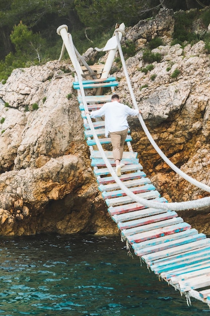 L'uomo che cammina dal ponte sospeso attraversa il mare