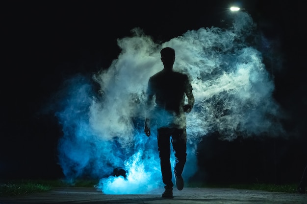 L'uomo che cammina nel fumo blu sullo sfondo scuro