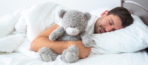 L'uomo che dorme con un peluche sullo sfondo bianco