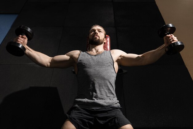 L'uomo che fa il braccio si solleva con i manubri in palestra