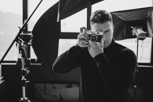 L'uomo che guarda attraverso il mirino dell'obiettivo della fotocamera per mancini sta puntando verso lo spettatore scatta la foto dal finestrino dell'auto fuori fuoco