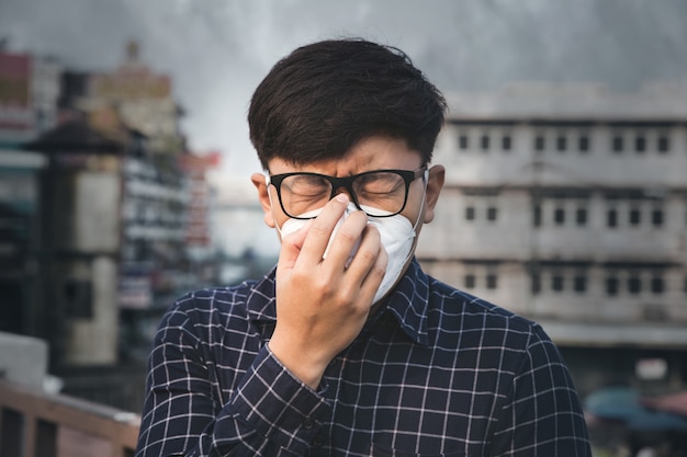 L'uomo che indossa la maschera di protezione respiratoria contro l'inquinamento atmosferico e le particelle di polvere supera i limiti di sicurezza. Concetto di assistenza sanitaria, ambientale, ecologia.