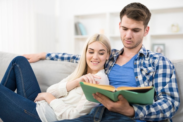 L'uomo che legge il libro vicino alla donna su un divano