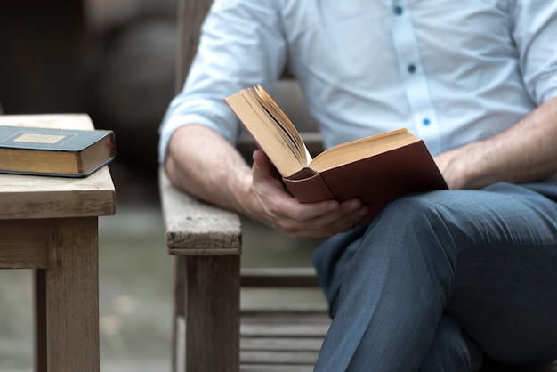 L&#39;uomo che legge un libro su una sedia nel parco, le persone di successo leggono al mattino ogni giorno.