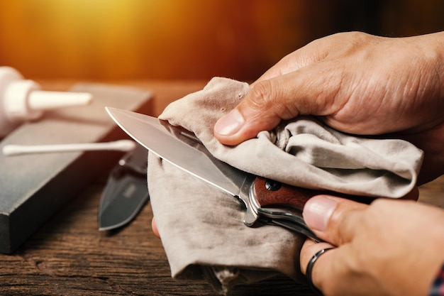 L'uomo che olia il suo coltello da tasca Concetto di cura e manutenzione del coltello da tasca