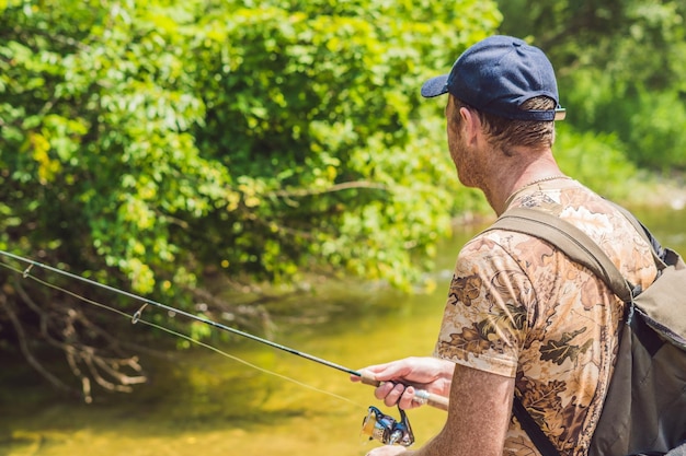 L'uomo che pesca su un fiume di montagna con uno spinning ultraleggero usando wobblers da pesca ha preso il suo amo