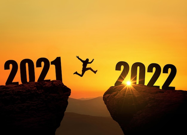 L'uomo che salta sulla scogliera 2022 sopra il precipizio al tramonto incredibile. Il concetto di Capodanno. Simbolo di inizio e benvenuto del nuovo anno 2022. La gente entra nell'anno 2022, idea creativa