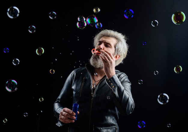 L'uomo che soffia bolle bolle di sapone gioca con le bolle uomo barbuto che soffia bolle di sapone felicità bambino