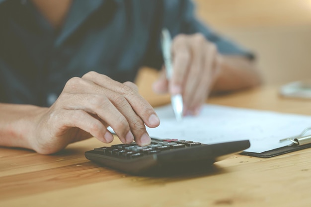 L&#39;uomo che utilizza la calcolatrice e la scrittura prende nota con il calcolo del costo