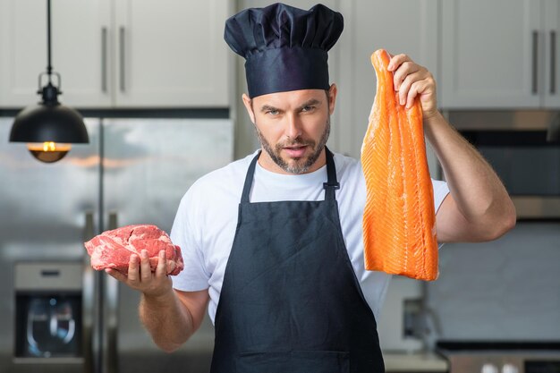 L'uomo chef fornello tiene pesce e carne salmone e manzo chef maschio in uniforme chef con carne cruda manzo e