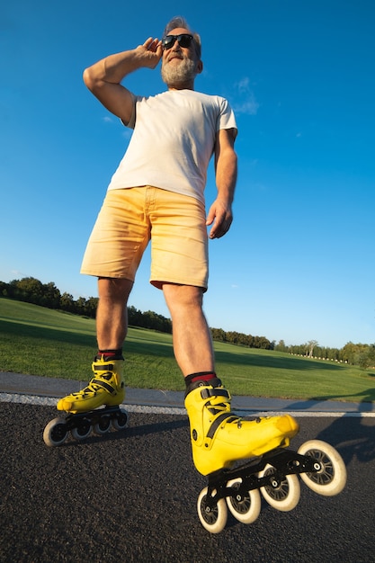 L'uomo con gli occhiali da sole in piedi sui rulli sulla strada