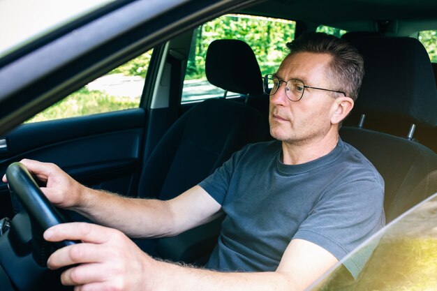 L'uomo con gli occhiali guida l'auto. Vecchia generazione al volante.