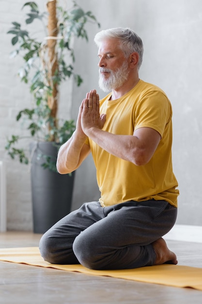 L'uomo con i capelli grigi medita e fa esercizi di respirazione, fitness ed esercizi fisici