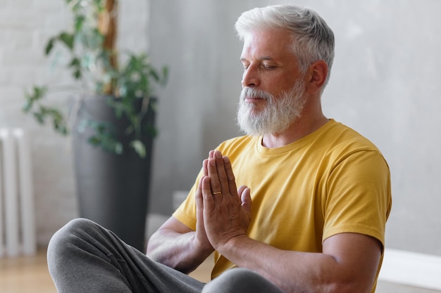 L'uomo con i capelli grigi medita e fa esercizi di respirazione, fitness ed esercizi fisici