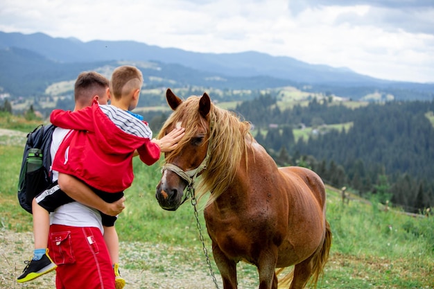 L'uomo con il bambino accarezza le montagne del cavallo sul concetto di viaggio di sfondo