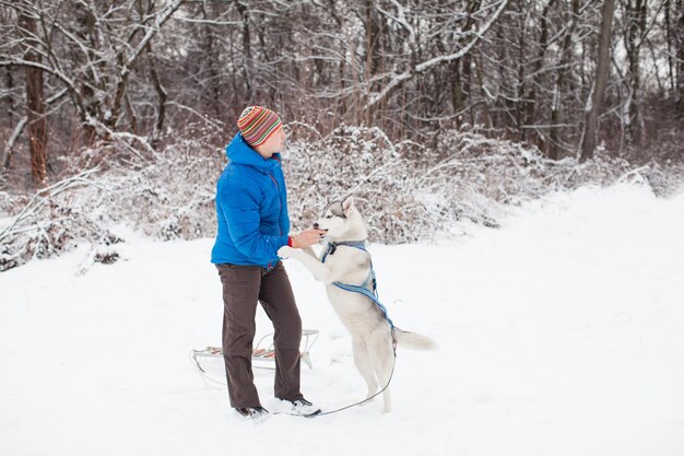 L'uomo con il cane husky sta camminando al parco innevato invernale.