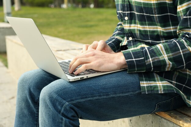 L'uomo con il computer portatile lavora nel parco. Lavoro all'aperto