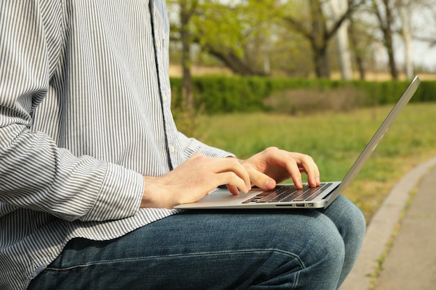 L'uomo con il computer portatile lavora nel parco. Lavoro all'aperto