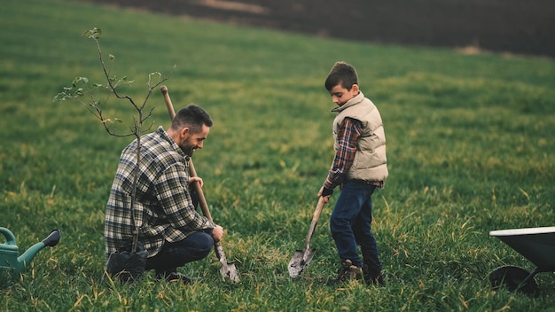 L'uomo con il figlioletto che pianta un albero nel campo