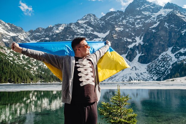 L'uomo con la bandiera ucraina è in piedi sulla riva di un lago Morskie Oko