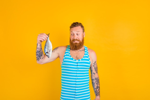 L'uomo con la barba e il costume da bagno ha pescato un pesce