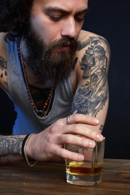 L'uomo con la barba e il tatuaggio bevono whisky