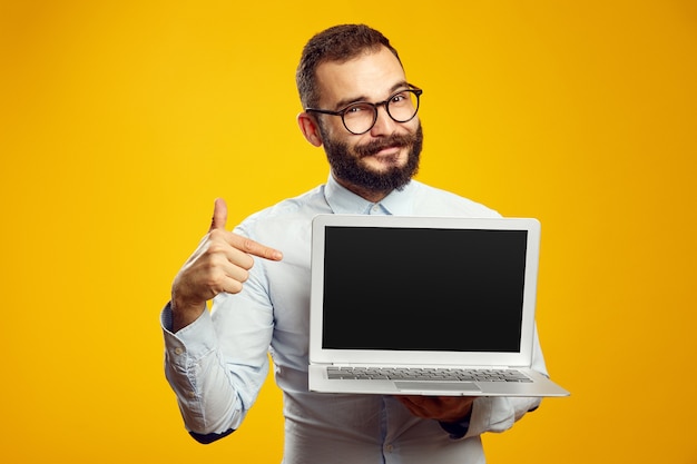 L'uomo con la barba indossa una maglietta beige e gli occhiali puntano al nuovo computer portatile dentro