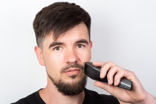 L'uomo con la barba si rade la barba con un rifinitore