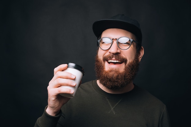 l'uomo con la barba sta tenendo il suo take away tazza di caffè o tè.