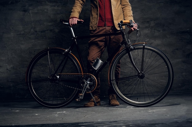 L'uomo con la sua bicicletta sta posando per il fotografo in uno studio fotografico scuro.