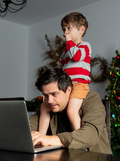 L'uomo con un bambino sta lavorando sodo con il laptop in ufficio a casa durante la pandemia