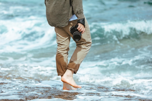 L'uomo con un professionista è venuto in mano camminando lungo la spiaggia rocciosa del mare