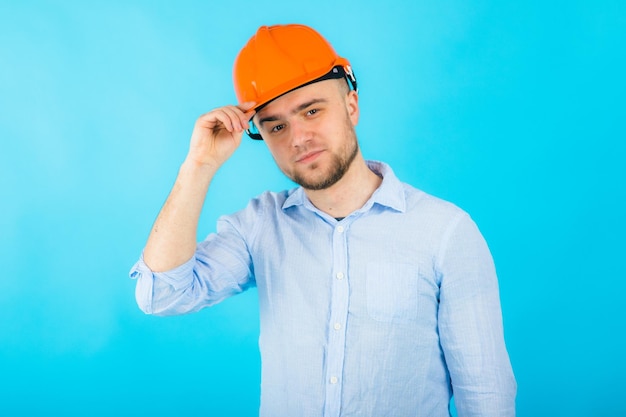 l'uomo con una camicia blu con un casco protettivo arancione si trova su uno sfondo blu