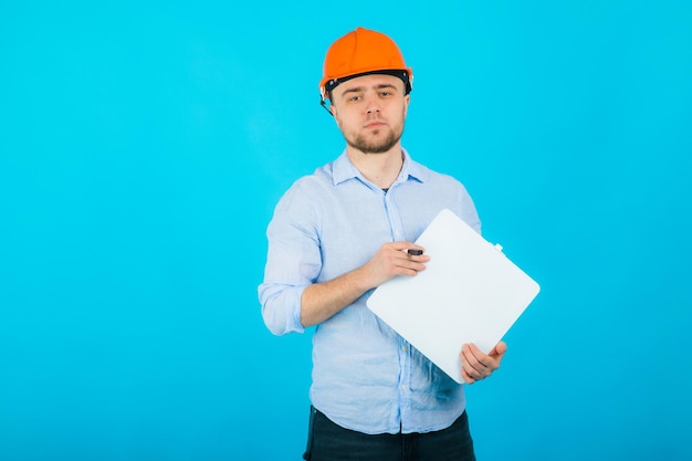 l'uomo con una camicia blu con un casco protettivo arancione si trova su uno sfondo blu