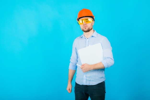 l'uomo con una camicia blu con un casco protettivo arancione si trova su uno sfondo blu