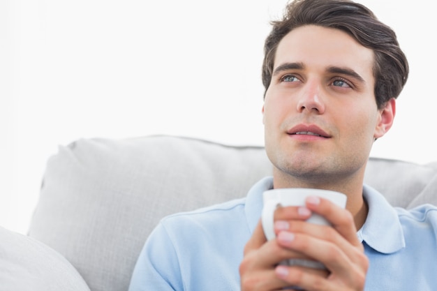 L&#39;uomo con una tazza di caffè si sedette sul divano