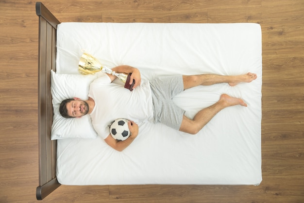 L'uomo con una tazza e una palla che dorme nel letto. vista dall'alto