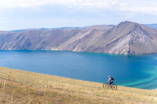 L'uomo con uno zaino va in bicicletta su per la montagna