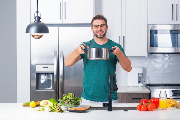 L'uomo cucina in cucina chef cuoco uomo prepara un piatto con il cibo nella ricetta del menu casseruola sano