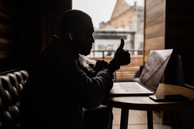 L'uomo d'affari afroamericano soddisfatto che mostra il pollice in su conduce una consultazione online ed è eccitato