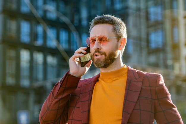 L'uomo d'affari alla moda ha una chiamata al cellulare uomo d'affari all'aperto che ha una chiamata al cellulare